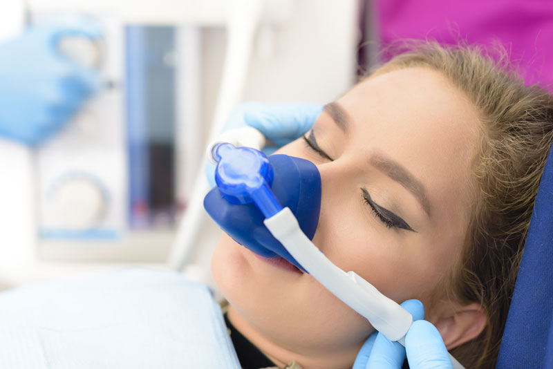 a dental implant patient inhaling nitrous oxide for her sedation dentistry needs.