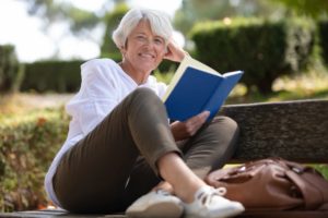 an older woman smiling and reading a book.