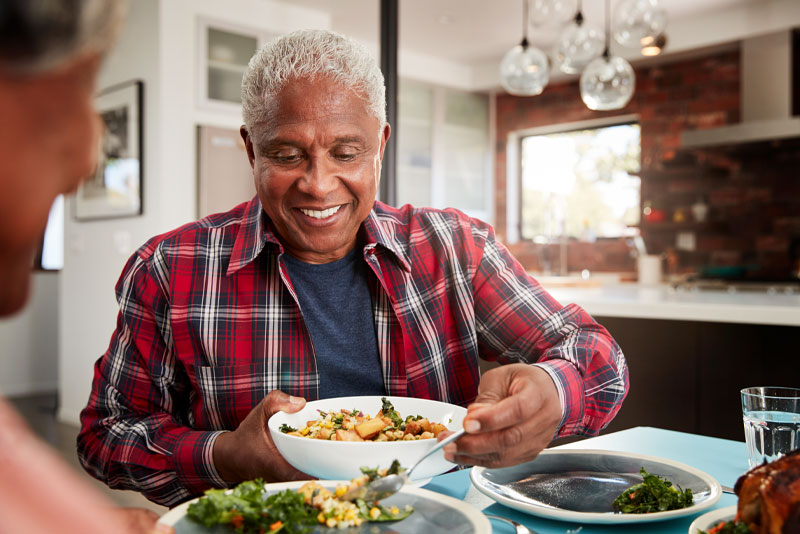image of a patient smiling as he eats his food because digital smile design technology was used to accurately place his dental implants.