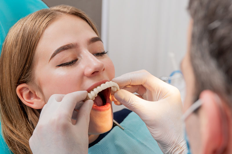 a patient getting a new smile in one day because a temporary prosthesis is being placed on her dental implants during her full mouth dental implant procedure.